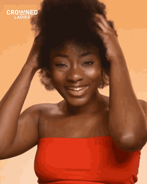 a woman in a red top is smiling in front of a crowned ladies logo