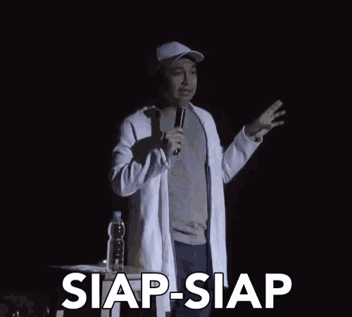 a man in a white coat is holding a microphone and the word siap-siap is above him