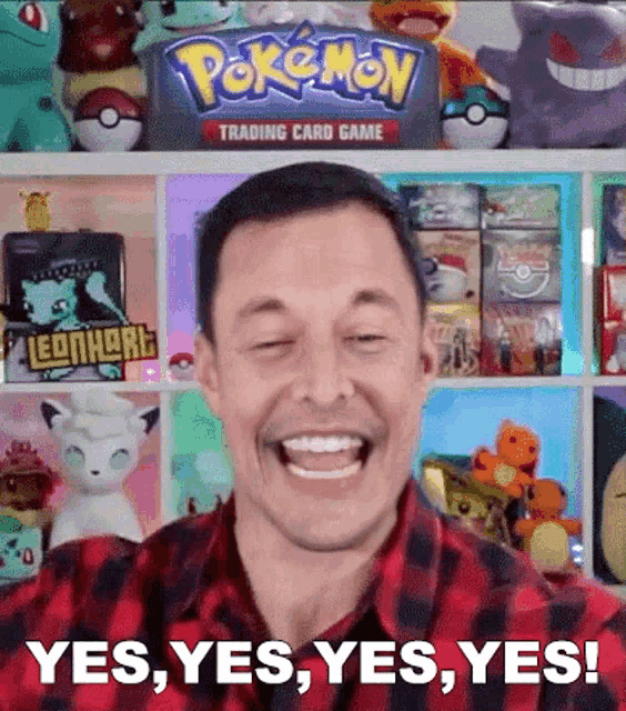 a man is smiling in front of a pokemon trading card game shelf .