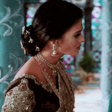 a woman wearing a necklace and earrings with a bun