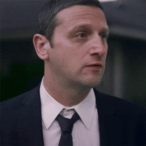 a man in a suit and tie looks to his left