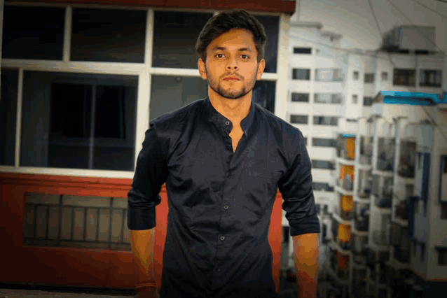 a young man wearing a black shirt stands in front of a building