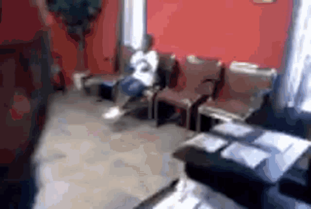 a man is sitting on a chair in a room with a red wall