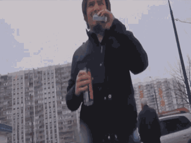 a man in a black jacket holds a can of coca cola in his right hand