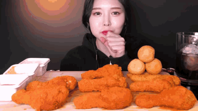 a woman is eating fried chicken on a wooden cutting board