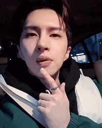 a young man wearing a ring on his finger is sitting in a car