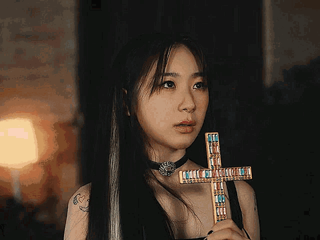 a woman is holding a cross in her hand and has a tattoo on her arm
