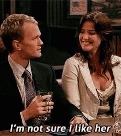 a man and a woman are sitting at a table and the man is holding a glass of beer .