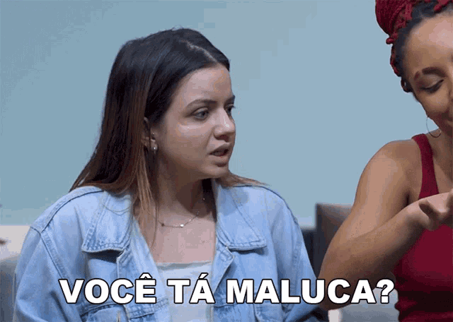 a woman in a denim jacket is talking to another woman and the words você ta maluca are above her