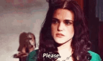 a woman with long dark hair is wearing a green sweater and a necklace and says please .