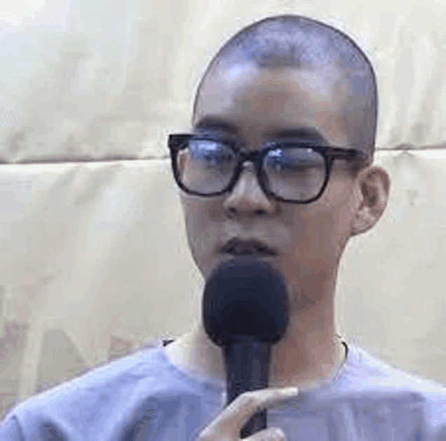 a man with glasses is talking into a microphone .