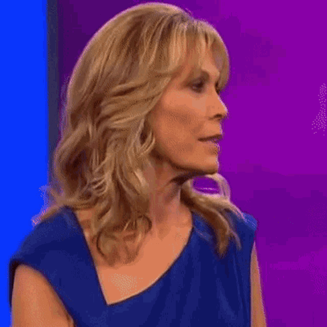 a woman in a blue dress is smiling with her hands outstretched