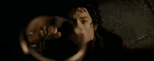 a man is holding a ring on his finger in a dark room