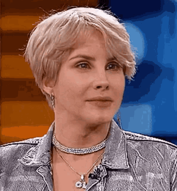 a woman wearing a choker and a denim jacket is looking at the camera .