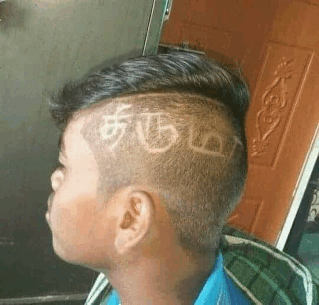a young boy with a shaved design on his head has the word tamil written on it .