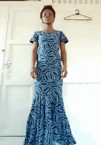a woman in a long blue dress is standing in front of a door .