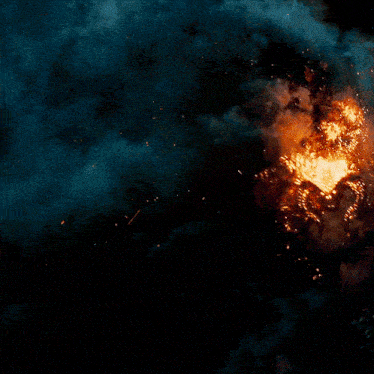 a large pile of wood is on fire with sparks coming out of it
