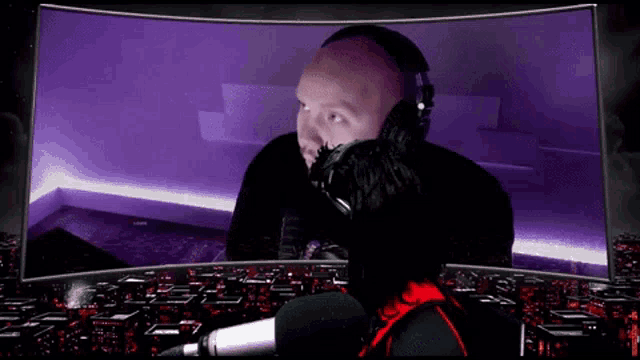 a man wearing headphones is talking into a microphone in front of a purple screen