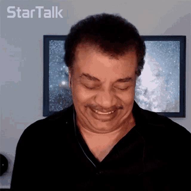 a man with a mustache is smiling in front of a star talk poster