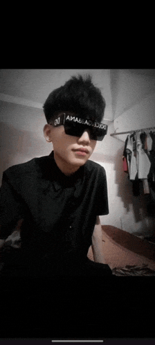a young man wearing sunglasses and a black shirt with the letter j on it