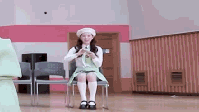 a woman in a green dress and white socks is sitting on a chair and smiling .