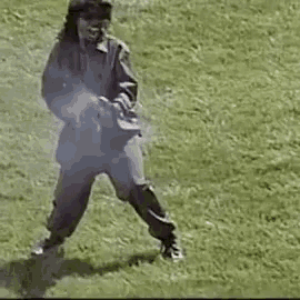 a man in a military uniform is holding a gun in a grassy field .