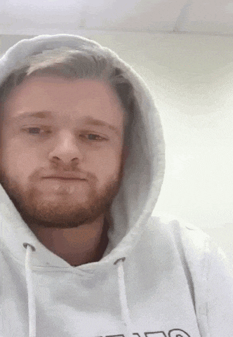 a man with a beard is wearing a white hoodie with the letter g on the front