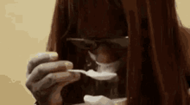 a woman is holding a spoon in front of her face and eating something .