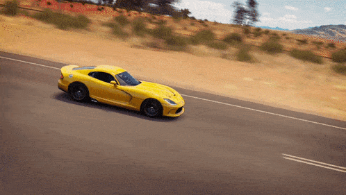 a yellow sports car driving down a road