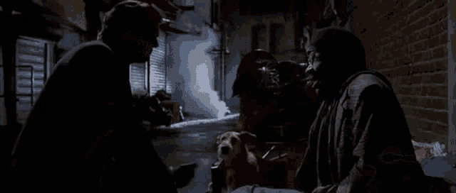 a man and a dog are sitting on the ground in a dark alleyway .