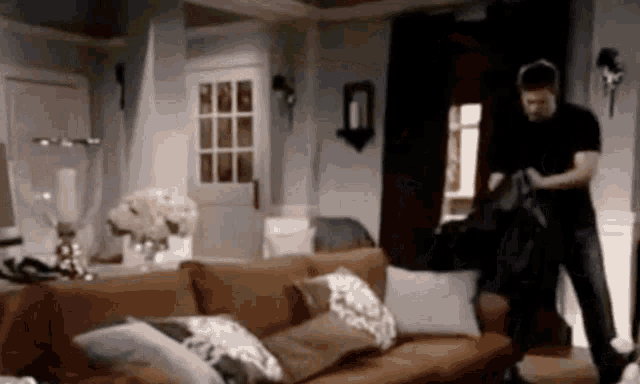 a man is standing in front of a couch in a living room