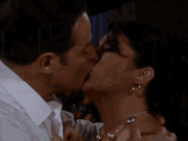 a man is kissing a woman 's neck while she wears a necklace .