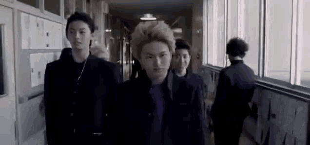 a group of young men are walking down a hallway together .