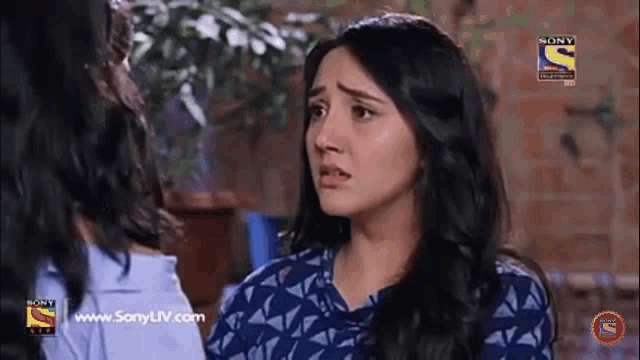 a woman in a blue shirt is talking to another woman in a blue shirt .