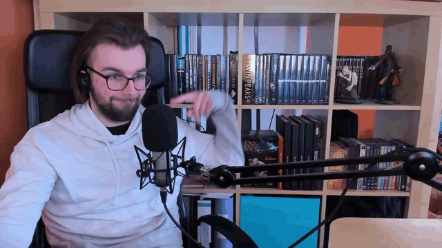 a man sitting in front of a microphone with a book called dark cats on the shelf