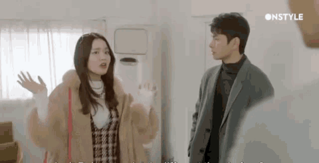 a man and a woman are standing next to each other in a room and talking .