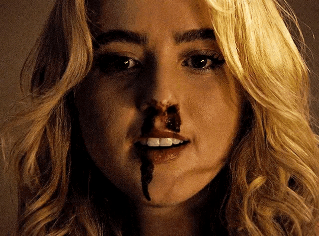 a close up of a woman 's face with blood on her nose
