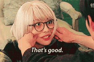a woman wearing glasses and a wig is being touched by a man and the words that 's good are visible .