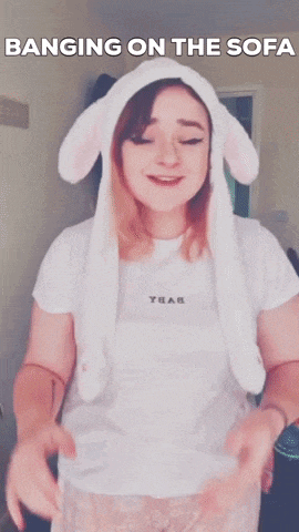 a woman wearing a bunny ear hat is banging on the couch