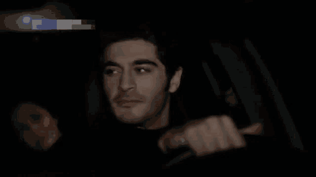 a woman in a red jacket is sitting in a car at night and smiling .