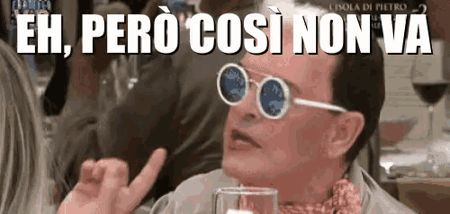 a man wearing sunglasses is sitting at a table with a glass of wine and says eh pero così non va