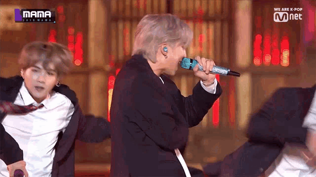 a man in a suit singing into a microphone with the words we are k-pop on the bottom