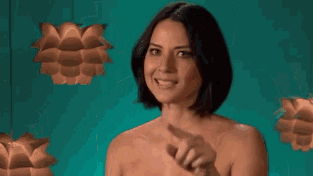 a woman without a shirt is making a funny face in front of a green background .