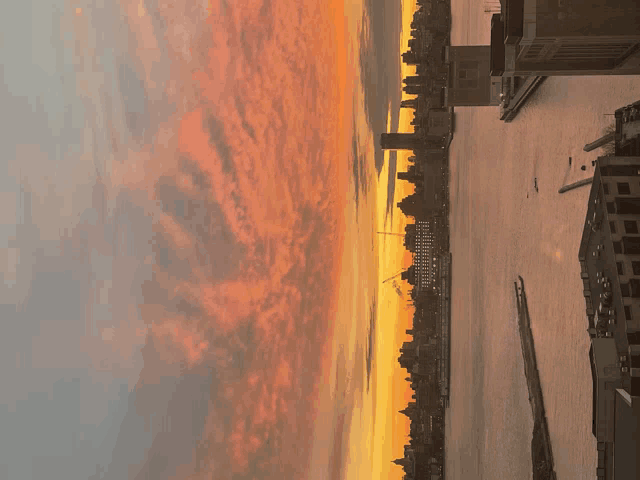 a sunset over a body of water with a few buildings in the foreground