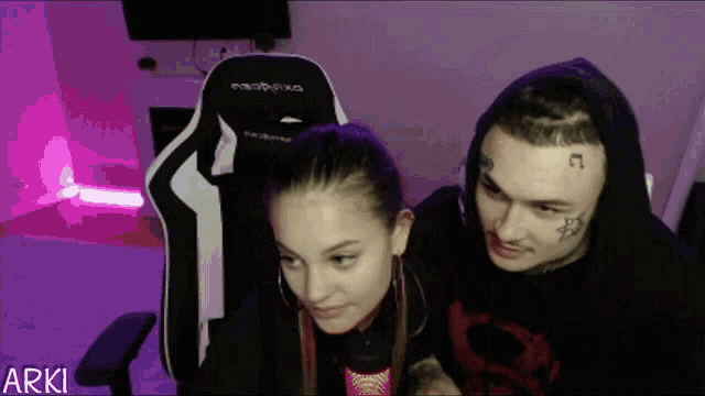 a man and a woman are sitting next to each other with the word arki on the bottom left
