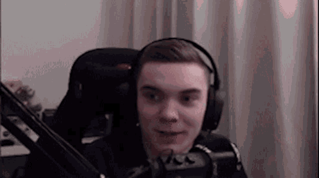 a young man wearing headphones and a microphone is sitting in front of a microphone .
