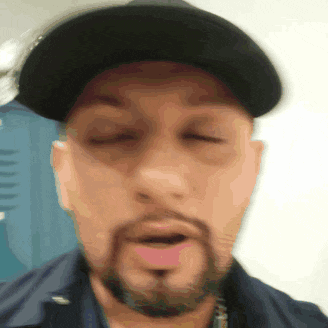a man with a beard is wearing a black hat and making a funny face