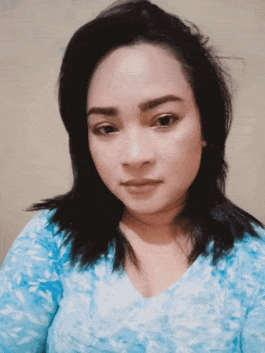 a woman wearing a blue shirt looks at the camera