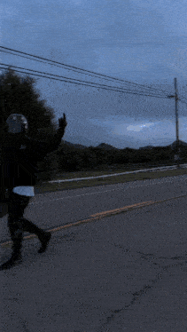 a person wearing a helmet is walking down a street and giving the middle finger