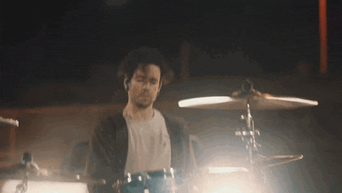 a man is playing drums in a dark room in a dark room .